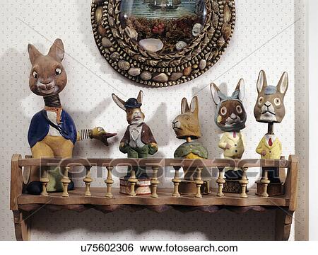Stock Photograph - COLLECTIONS: ENID HUBBARD RABBITS: Wooden spool shelf holds five paper Mache nodder rabbits, shell art hangs above. Fotosearch