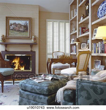 Stock Image - Comfortable seating furniture in front of fireplace and book shelves. Fotosearch
