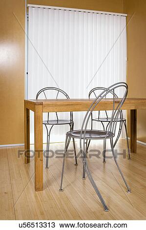 Stock Image - Contemporary metal chairs at wooden dining table. Fotosearch