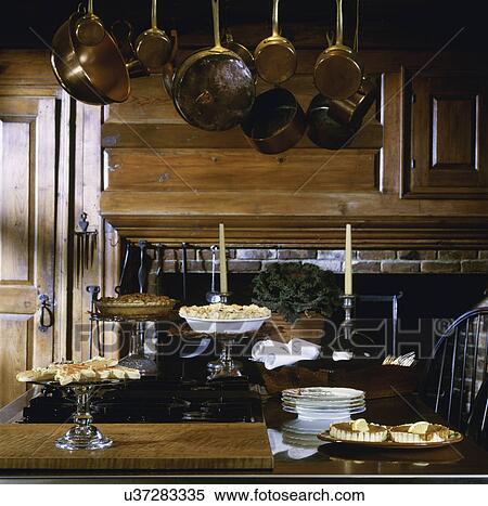 Stock Photography - Cooking island set with desserts and antique hanging copper pots and utensils, USA. Fotosearch