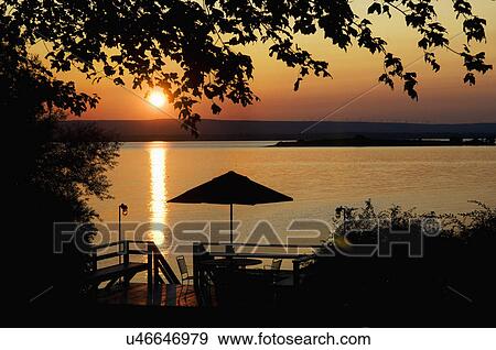 Stock Photo - Deck silhouetted against lake at sunset, Grand Isle, Vermont, USA. Fotosearch
