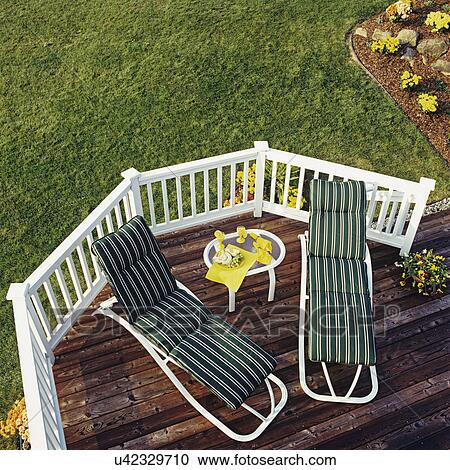 DECKS: Bird's eye view of two recliners with striped green cushions, yellow flowers and napkins on cener table, white railings, lawn, flower beds. View Large Photo Image Stock Image - DECKS: Bird's eye view of two recliners with striped green cushions, yellow flowers and napkins on cener table, white railings, lawn, flower beds. . Fotosearch