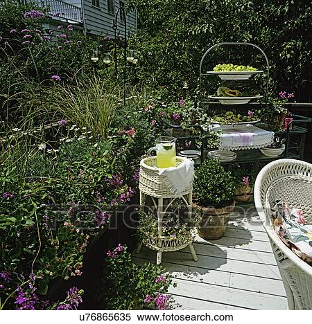 DECKS: Deck with lots of potted plants, container gardens and white wicker furniture. Metal Bakers rack set with food. View Large Photo Image Stock Photography - DECKS: Deck with lots of potted plants, container gardens and white wicker furniture. Metal Bakers rack set with food. . Fotosearch