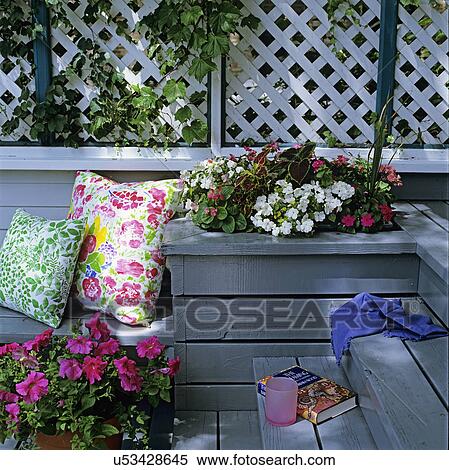 Stock Photography - DECKS: Detail of built-in-planter on grey outdoor deck. Flowers, colorful pillows. Lattice work.. Fotosearch