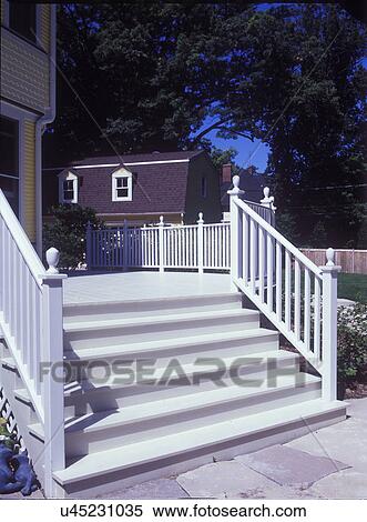 Stock Photography - DECKS: Exterior steps leading to a white wooden deck of a remodeled yellow Victorian home, railing and banister,. Fotosearch