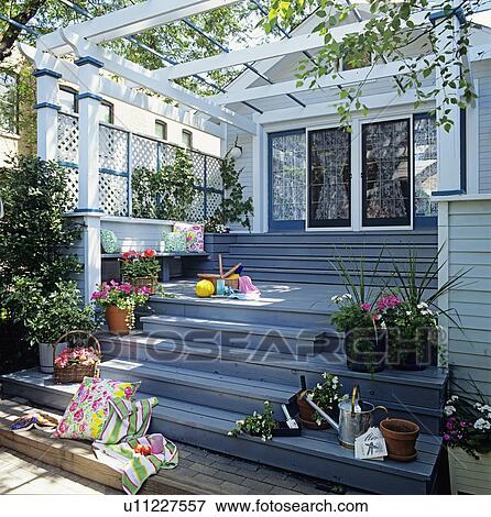 Stock Photo - DECKS: pergola attached to the house, multi leveled decking, container gardens, built in seating along lattice wall of pergola, looking toward house and windows . Fotosearch