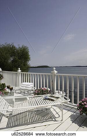 DECKS; upper deck of three story lake home, chaise lounges, pink flowers in containers, line repetition View Large Photo Image Picture - DECKS; upper deck of three story lake home, chaise lounges, pink flowers in containers, line repetition. Fotosearch