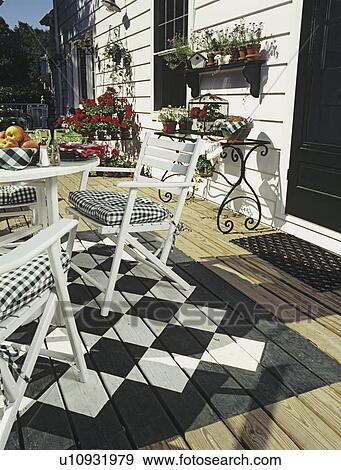 DECKS: White patio table and chairs. Black and white checker board design painted under eating area, potted plants, kitchen in view thru open door. View Large Photo Image Stock Photo - DECKS: White patio table and chairs. Black and white checker board design painted under eating area, potted plants, kitchen in view thru open door. . Fotosearch