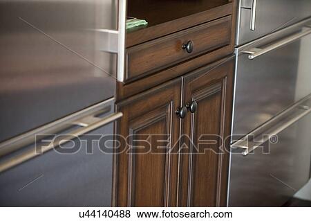 Stock Photo - Detail kitchen cabinets between two refrigerators; Irvine; California; USA. Fotosearch