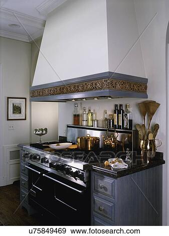 Stock Photo - Detail of ceramic border of hood over stainless professional range, drawers, granite counter top. Fotosearch
