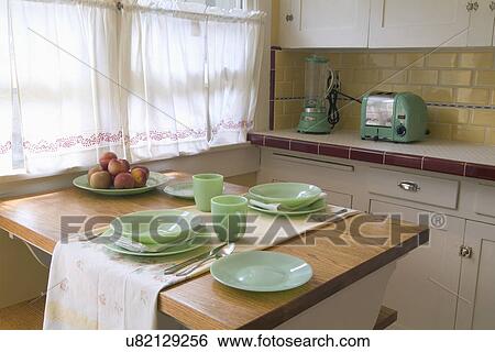 Stock Photograph - Detail place settings on kitchen table in small vintage kitchen; San Diego; California; USA. Fotosearch