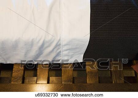 Stock Image - Detail sheet and blanket on bed on wood slated bed frame; Aliso Viejo; California; USA. Fotosearch
