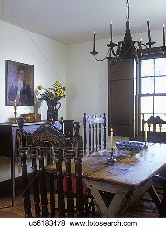 DINING ROOMS: Antiques, banister back chairs, sawbuck table, tin chandelier, sideboard, vase of sunflowers, oil portrait, shutters, period colonial View Large Photo Image Stock Photo - DINING ROOMS: Antiques, banister back chairs, sawbuck table, tin chandelier, sideboard, vase of sunflowers, oil portrait, shutters, period colonial . Fotosearch
