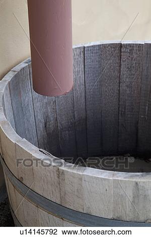 Stock Image - Drain pipe dripping into wooden barrel; Bakersfield; California; USA. Fotosearch