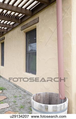 Stock Photo - Drain pipe dripping into wooden barrel; Porterville; California; USA. Fotosearch