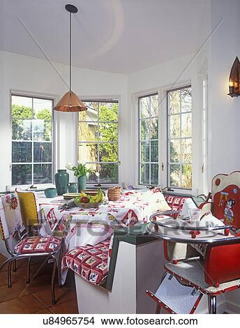 Picture - EATING AREAS: Built in benches in breakfast nook, vintage cloth upholstery, vintage 50's chrome and vinyl chairs, vintage tablecloths, green art pottery, copper pendant lighting, vintage baby highchair in foreground, wall of windows. Fotosearch