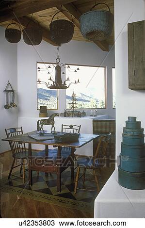 EATING AREAS: Rustic eating area with wicker baskets hanging from exposed beams. Hobby horse, blue taupe color scheme, modern space, painted floor cloth, stack of blue shaker boxes View Large Photo Image Stock Image - EATING AREAS: Rustic eating area with wicker baskets hanging from exposed beams. Hobby horse, blue taupe color scheme, modern space, painted floor cloth, stack of blue shaker boxes. Fotosearch