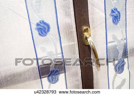 Stock Image - Embroidered sheer curtains in front of window; Italy. Fotosearch