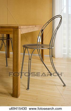 Stock Image - Empty chair by dining table on hardwood floor, San Diego, California, USA. Fotosearch
