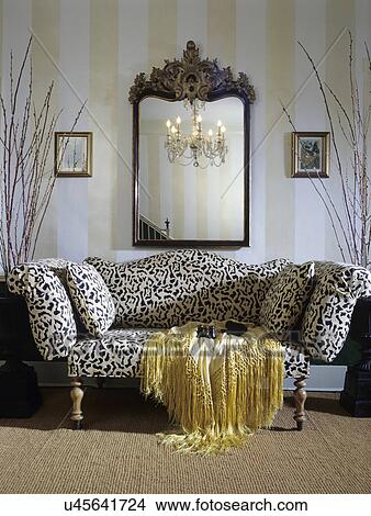 Picture - entry hall: Sofa with leopard print, gilded mirror, painted stripe wall, sisel wall to wall carpet . Fotosearch