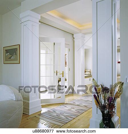 Stock Photo - Entry halls: white French doors open into entrance hall from small foyer, light stained wood floors, four columns add formality, arts and craft style, southwestern theme rug . Fotosearch