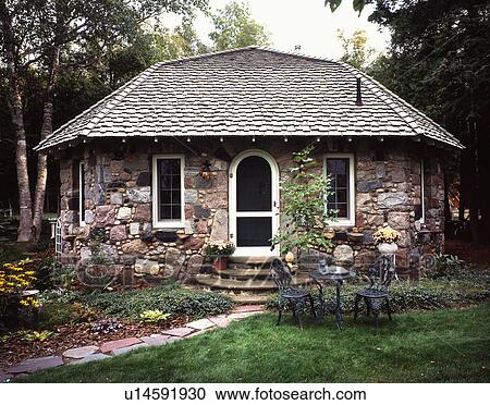 Stock Image - Exterior front view of a stone cottage with shingled roof at Charlevoix; Missouri; USA. Fotosearch