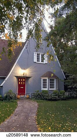 Stock Photo - Exterior gray cottage style house with pointed roof and red door at Chico; California; USA. Fotosearch