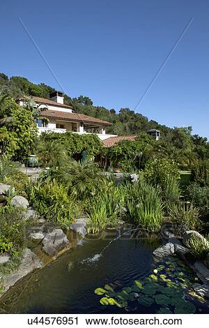 Stock Image - Exterior of a house nearby pond against clear sky, California, USA. Fotosearch