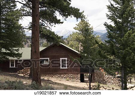 Stock Photo - Exterior of residential structure with trees and stone wall. Fotosearch