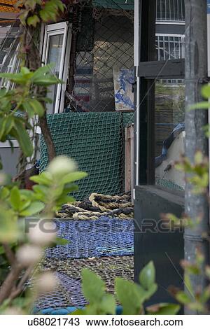 Stock Image - Exterior view of cottage with rope and commercial fishing nets. Fotosearch
