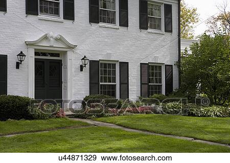 EXTERIOR: White brick traditional colonial home with black shutters, pediment above the door, View Large Photo Image Stock Photo - EXTERIOR: White brick traditional colonial home with black shutters, pediment above the door,. Fotosearch