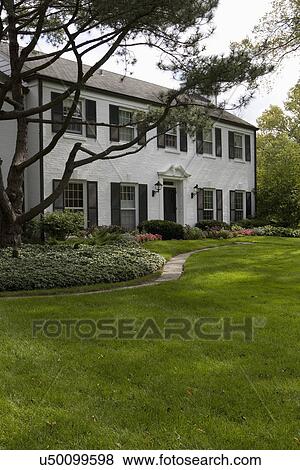 EXTERIOR: White brick traditional colonial home with black shutters, pediment above the door, View Large Photo Image Stock Photo - EXTERIOR: White brick traditional colonial home with black shutters, pediment above the door,. Fotosearch