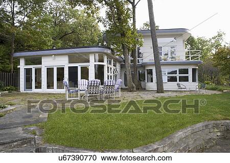 EXTERIORS: Art Deco home built in 1935, limestone patio with trees in the middle, retaining wall, striped cushions on patio furniture, upper deck to right, flat roof with curved corners View Large Photo Image Stock Image - EXTERIORS: Art Deco home built in 1935, limestone patio with trees in the middle, retaining wall, striped cushions on patio furniture, upper deck to right, flat roof with curved corners. Fotosearch