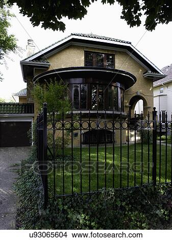 EXTERIORS: brick bungalow with curved front, fence in foreground, garage to left green tile roof View Large Photo Image Picture - EXTERIORS: brick bungalow with curved front, fence in foreground, garage to left green tile roof. Fotosearch
