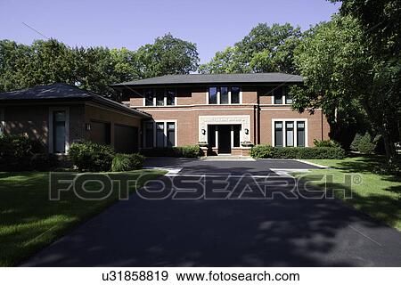 Stock Photo - EXTERIORS: Brick contemporary Prairie style home with blacktop driveway leading up to home, summer trees. Fotosearch