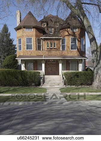 Stock Image - EXTERIORS: Cedar shake three story home, with gothic windows, and three small dormers, porch with carved fretwork,. Fotosearch