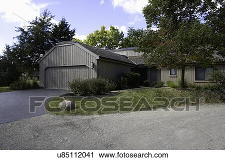 Stock Image - EXTERIORS: condo with wood vertical siding facing garage, road in foreground. Fotosearch