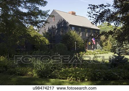 EXTERIORS: Dark brown salt box style home, sweeping lawns, gardens, American flag, shaded garden in foreground, horizontal View Large Photo Image Stock Photo - EXTERIORS: Dark brown salt box style home, sweeping lawns, gardens, American flag, shaded garden in foreground, horizontal. Fotosearch