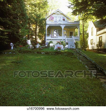 EXTERIORS: Front view with lawn of Victorian cottage, pale yellow with white trim, porch, summer time. View Large Photo Image Stock Photograph - EXTERIORS: Front view with lawn of Victorian cottage, pale yellow with white trim, porch, summer time.. Fotosearch