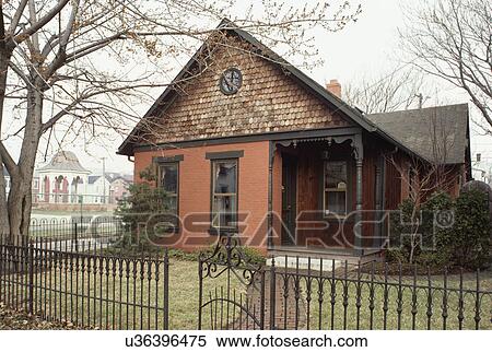 Stock Photography - EXTERIORS: One story and a half story single family brick Victorian house, brick walkway and small yard surrounded with a wrought iron fence, small porch, cedar siding and painted brick. Fotosearch