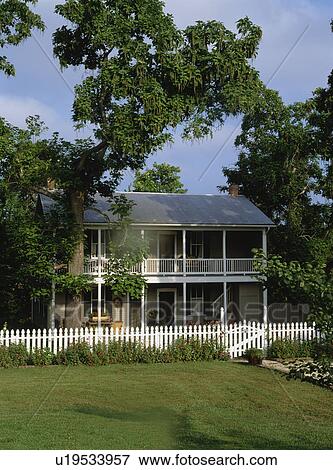 Stock Photo - EXTERIORS: Two story home, white picket fence, porches on both levels run the length of the house, vertical. Fotosearch
