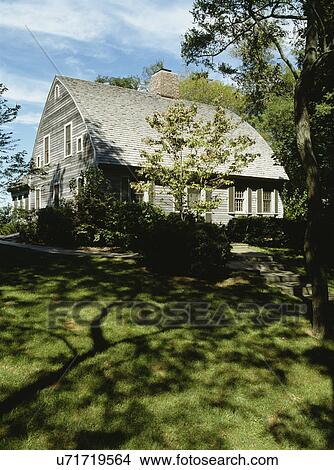 Picture - EXTERIORS: Two story single family New England style cape cod house with window shutters, sidewalk with steps, and large yard with lawn and trees, heavily shaded, cedar shake roof. Fotosearch