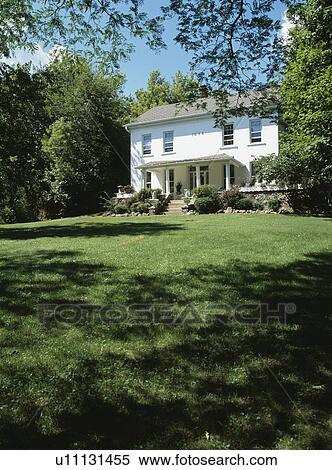 EXTERIORS: Two story single family stucco 1840 farmhouse in a Georgian Colonial style, front porch with concrete steps, large lawn in front, mature trees surround View Large Photo Image Stock Photography - EXTERIORS: Two story single family stucco 1840 farmhouse in a Georgian Colonial style, front porch with concrete steps, large lawn in front, mature trees surround. Fotosearch