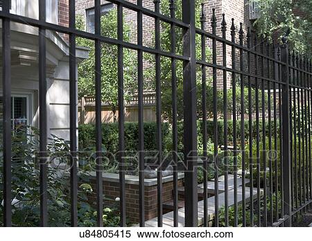 FENCES: Black iron fence, city garden behind View Large Photo Image Stock Photography - FENCES: Black iron fence, city garden behind. Fotosearch