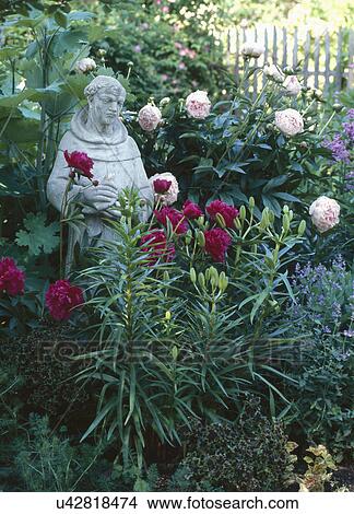 Picture - Figurine surrounded by flower plants in garden. Fotosearch