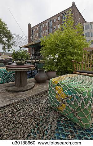 Stock Image - Floating buoys covered in fishing net with armchair in front of cottage. Fotosearch