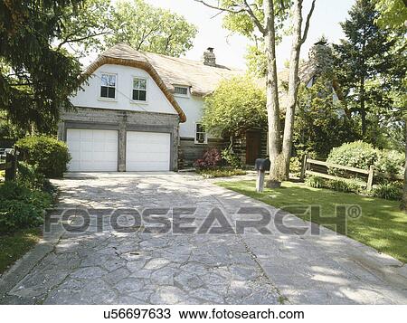 Stock Image - Front exterior of driveway leading to garage of traditional home. Fotosearch