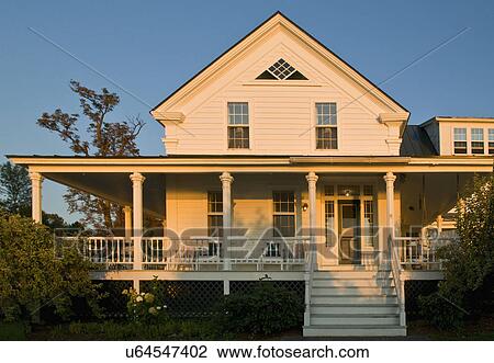 Stock Image - Front exterior traditional home with wrap around porch, Grand Isle, Vermont, USA. Fotosearch