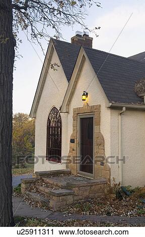 Stock Image - Front exterior view of white cottage with stone stairs and pointed rooftops; Minneapolis; Minnesota; MN. Fotosearch