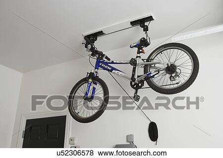GARAGE: Inside garage, new construction, a bicycle is suspended from ceiling, bike is lowered by a pulley system View Large Photo Image Stock Photo - GARAGE: Inside garage, new construction, a bicycle is suspended from ceiling, bike is lowered by a pulley system. Fotosearch